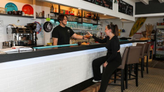 En gæst og bartender nyder aftenstemningen ved baren på Flower Camping Les Dunes i Pays de la Loire.