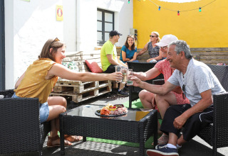 Gruppe voksne og unge nyder drikkevarer udenfor på Flower Camping Les Dunes, Pays de la Loire, Frankrig.