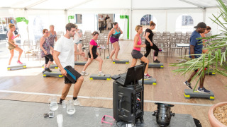 Træningshold i telt på Flower Camping Les Dunes i Pays de la Loire, Frankrig, med folk der træner step.
