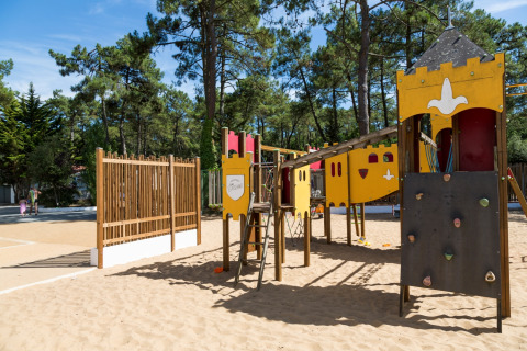 Legeplads med klatrestativ og sandbund i et skovområde på Flower Camping Les Dunes, Pays de la Loire, Frankrig.