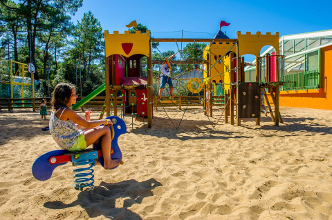 Bambini giocano in un parco giochi sabbioso con attrezzature colorate al Flower Camping Les Dunes, Pays de la Loire.