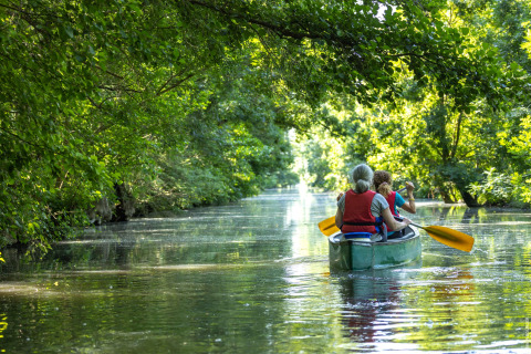 Twee mensen varen met een kano op een rustige rivier door het groen bij Longeville-sur-Mer in Frankrijk.