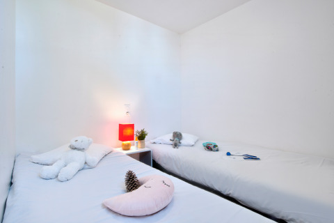 Værelse med to enkeltsenge, hvidt sengetøj, tøjdyr og natbord på Huis COMFORT, Flower Camping Les Ilates, Frankrig.