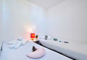 Værelse med to enkeltsenge, hvidt sengetøj, tøjdyr og natbord på Huis COMFORT, Flower Camping Les Ilates, Frankrig.