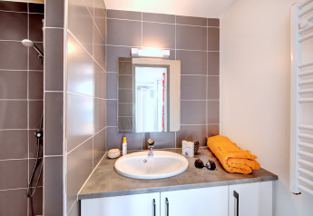 Moderne badeværelse i Huis COMFORT på Flower Camping Les Ilates med gråt flisebruseområde i Frankrig.