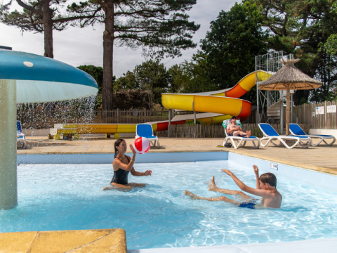 Kinderen en volwassenen genieten van het zwembad, de glijbaan en ligstoelen bij Flower Camping Port de la Chaîne.