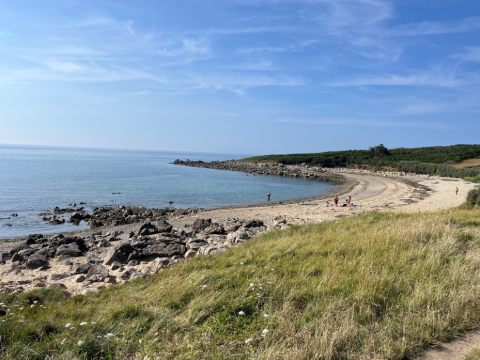 Vista costiera al Flower Camping Port de la Chaîne in Bretagna, Francia, con spiaggia rocciosa e mare calmo.