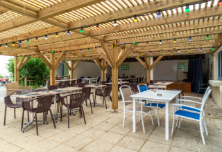 Terrasse couverte avec guirlandes lumineuses au Flower Camping Port de la Chaîne en Bretagne, France.