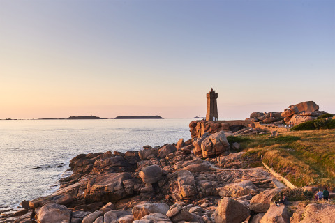 Sonnenuntergang an der Küste bei Pleubian, Bretagne, Frankreich, mit Leuchtturm und Felsen am Meer.