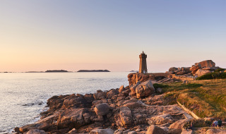 Coucher de soleil sur la côte près de Pleubian, Bretagne, France, avec un phare et des rochers au bord de la mer.