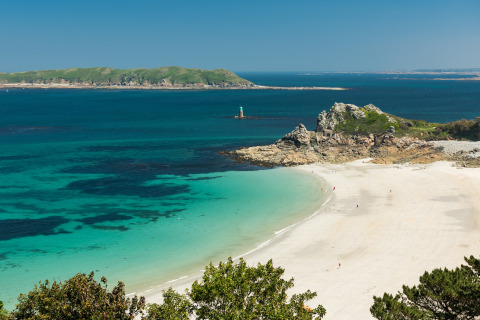 Kystlandskab nær Pleubian i Bretagne, Frankrig, med turkisblåt vand, sandstrand og grønne bakker.