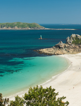 Paysage côtier près de Pleubian en Bretagne, France, avec eau turquoise, plage de sable et falaises verdoyantes.