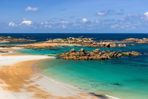 Sandstrand, türkisfarbenes Wasser und Felseninseln bei Flower Camping Port de la Chaîne in der Bretagne.
