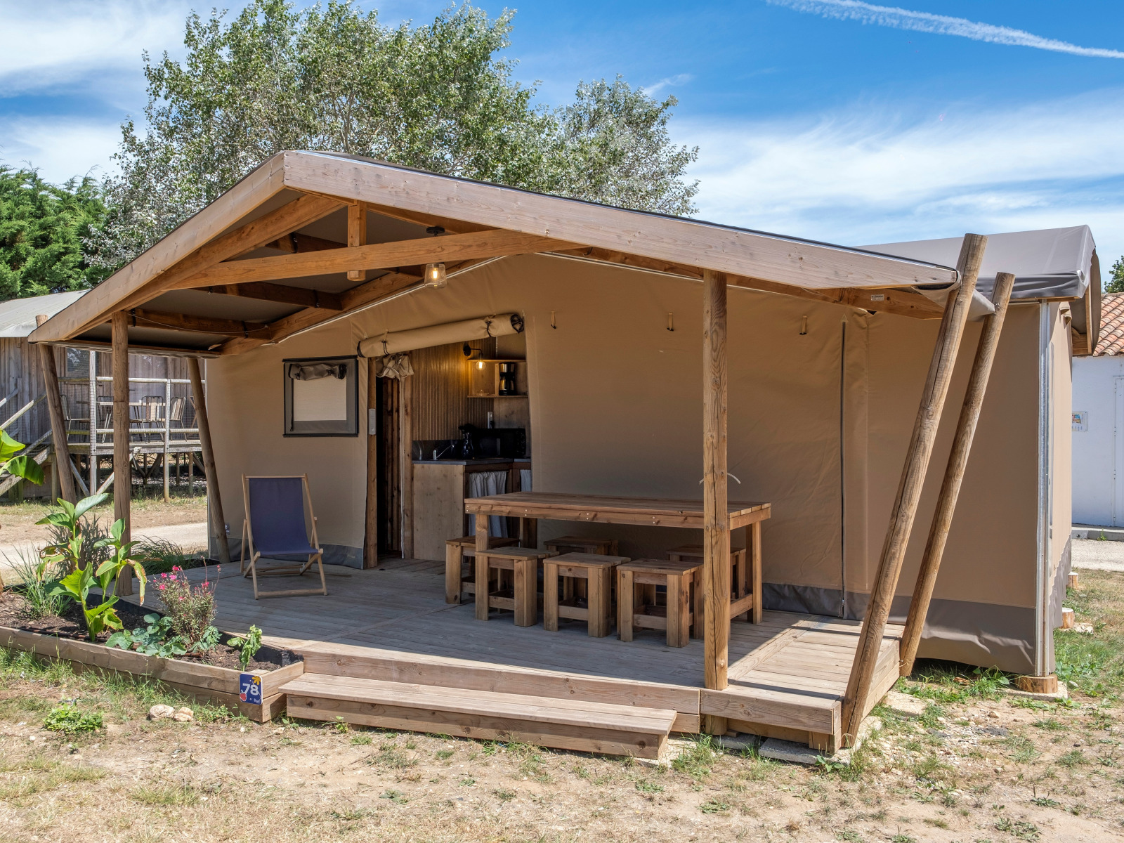 Safaritent bij Ecolodge cabine Cotton CONFORT met houten veranda, tuin en buitenzitjes.