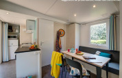 Binnenkant van Homeflower PREMIUM lodge met eetgedeelte, keuken, bankje en raam met tuinzicht.