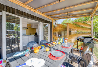 Überdachter Essbereich beim Glamping mit modernem Tisch, Frühstück und Blick auf die Natur.