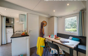 Moderne glampingaccommodatie met keuken, eettafel, zithoek, raam en vrolijke, kleurrijke decoratie.