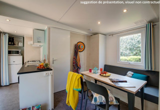 Moderne glampingaccommodatie met keuken, eettafel, zithoek, raam met uitzicht en kleurrijke accenten.
