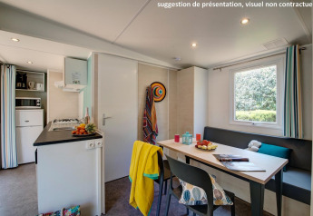 Moderne glampingaccommodatie met keuken, eettafel, zithoek, raam en vrolijke, kleurrijke decoratie.