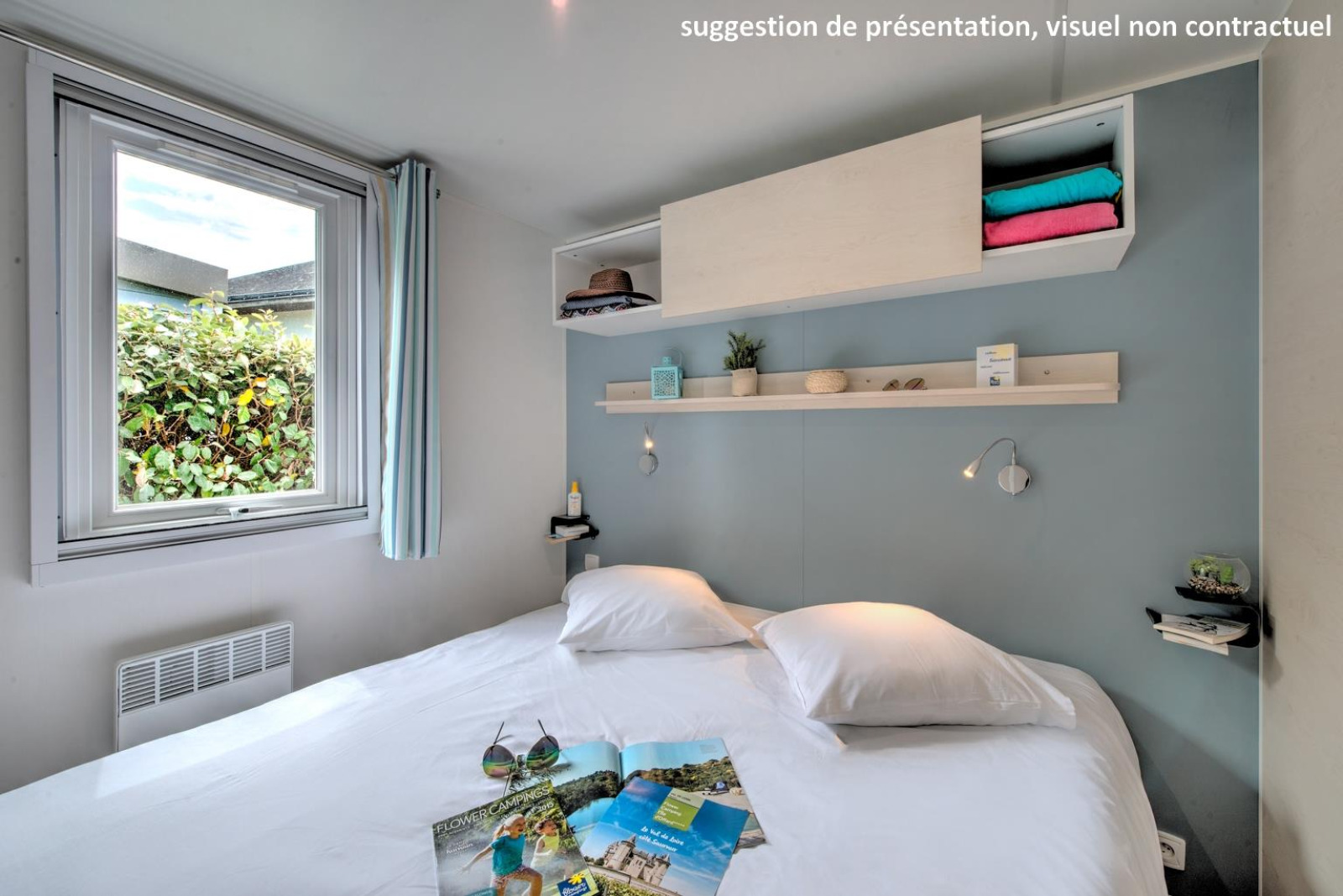 Moderne glamping slaapkamer met tweepersoonsbed, open raam, decoratieve planken en wit beddengoed.