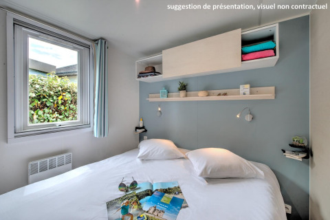 Moderne glamping slaapkamer met tweepersoonsbed, open raam, decoratieve planken en wit beddengoed.