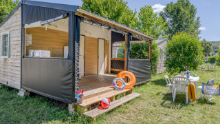 Cabaña Mobitoile Standaard con terraza abierta, muebles de jardín y césped verde en un entorno natural.