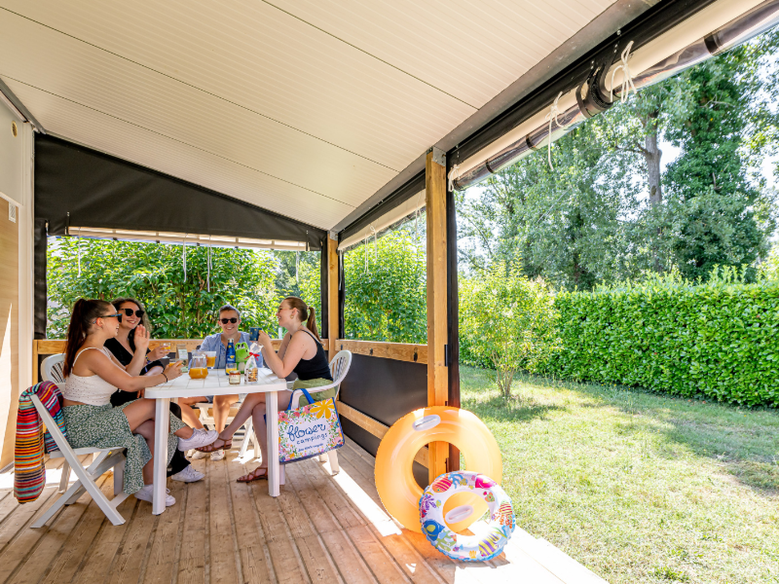 Vier mensen zitten samen op het terras van de Mobitoile Standaard bij Flower Camping Les Ondines in Frankrijk.