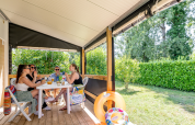 Cuatro personas conversan y disfrutan en la terraza de Mobitoile Standaard en Flower Camping Les Ondines, Francia.