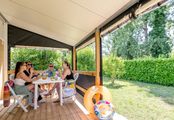Cuatro personas conversan y disfrutan en la terraza de Mobitoile Standaard en Flower Camping Les Ondines, Francia.