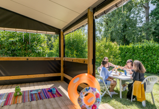 Gruppo che si gode un pasto all'aperto vicino alla cabina Mobitoile Standaard al Flower Camping Les Ondines.