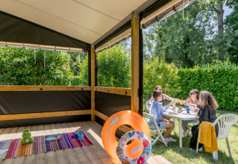 Familie nyder udendørs måltid ved et bord nær Mobitoile Standaard kabine på Flower Camping Les Ondines.