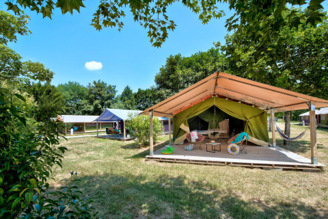 Safaritent Freeflower Standard bij Flower Camping Les Ondines in Frankrijk op een grasrijk, schaduwrijk veld.