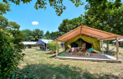 Safaritent Freeflower Standard bij Flower Camping Les Ondines in Frankrijk op een grasrijk, schaduwrijk veld.