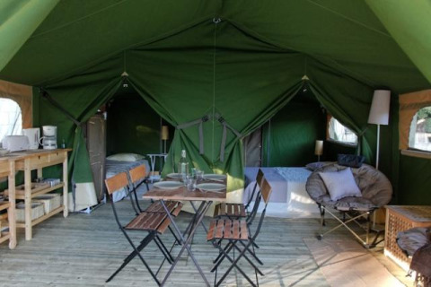 Binnenzicht van de Freeflower Standard safaritent op Flower Camping Les Ondines met eethoek en bedden.