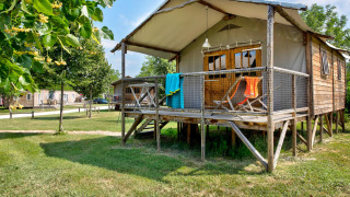 Cabane Lodge Confort: Eine erhöhte Holzhütte mit Veranda, Sonnenliegen und farbenfrohen Handtüchern.