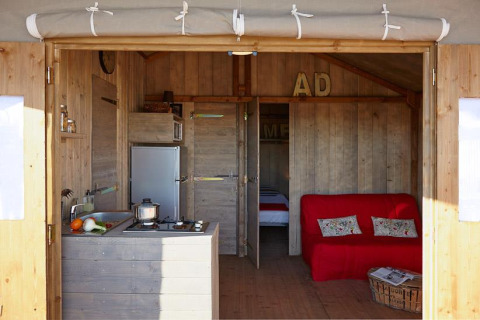 Binnenkant van Cabane Lodge Confort aan Flower Camping Les Ondines in Frankrijk met keuken en zithoek.