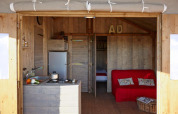 Binnenkant van Cabane Lodge Confort aan Flower Camping Les Ondines in Frankrijk met keuken en zithoek.