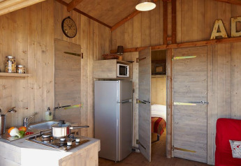 Interno della Cabane Lodge Confort al Flower Camping Les Ondines, Francia, con cucina e soggiorno.