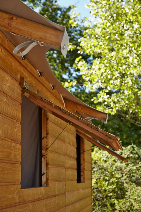 Houten hut met gebogen dak en open raam bij Cabane Lodge Confort, Flower Camping Les Ondines, Frankrijk.