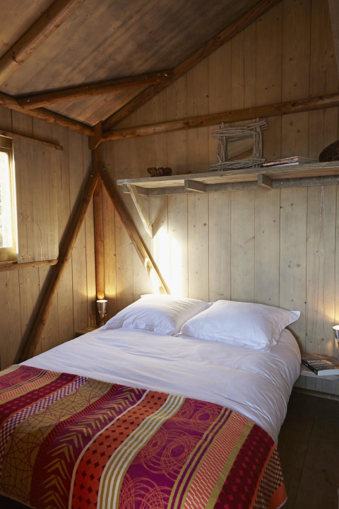 Acogedor dormitorio en la Cabane Lodge Confort de Flower Camping Les Ondines, Francia, con paredes de madera.