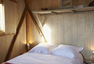 Accogliente camera da letto nella Cabane Lodge Confort al Flower Camping Les Ondines, Francia, con pareti in legno.