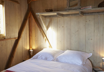 Acogedor dormitorio en la Cabane Lodge Confort de Flower Camping Les Ondines, Francia, con paredes de madera.