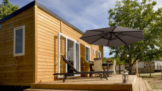 Zonnig terras bij Mobil-Home Premium Met airco, houten huis met tuinmeubels en grote parasol
