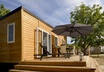 Zonnig terras bij Mobil-Home Premium Met airco, houten huis met tuinmeubels en grote parasol