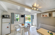 Bright glamping accommodation featuring dining table, sofa, fridge, and access to an outdoor terrace.