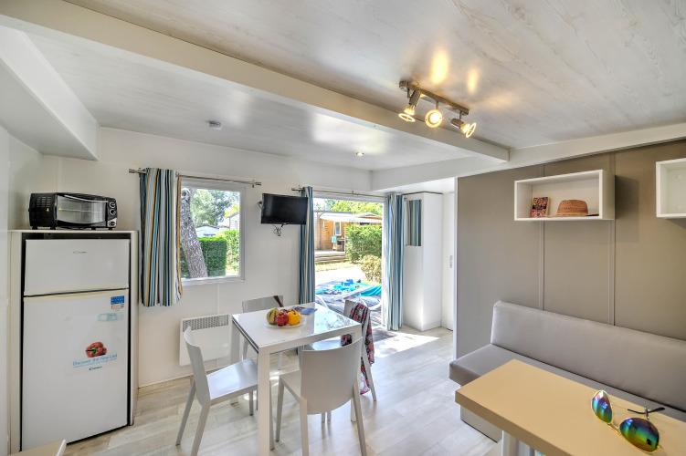 Bright glamping accommodation featuring dining table, sofa, fridge, and access to an outdoor terrace.