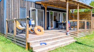 Homeflower Premium cabin met airco, zonnig terras, ligstoelen en groene grasveld rondom.