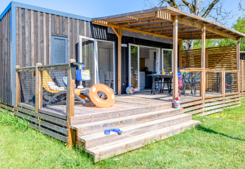 Træhytte Homeflower Premium med terrasse, liggestole og aircondition, omgivet af grønt græs.