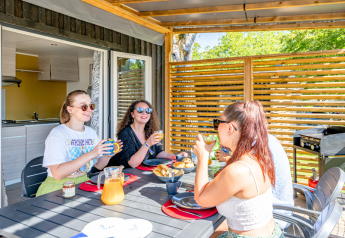 Fire unge voksne nyder morgenmad på terrassen i Homeflower Premium med aircondition på Flower Camping Les Ondines.