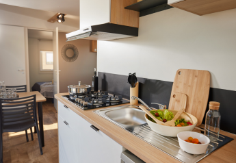 Moderne glampingkeuken met houten werkblad, gaskookplaat, spoelbak, vaatwasser en verse salade.